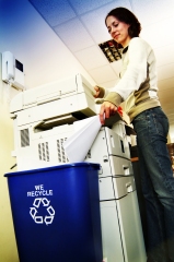 woman recycling paper into a blue recycling bin